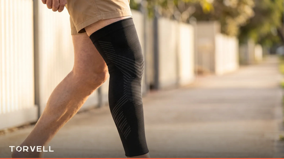 Man walking outdoors wearing a black full-leg knee compression sleeve Image